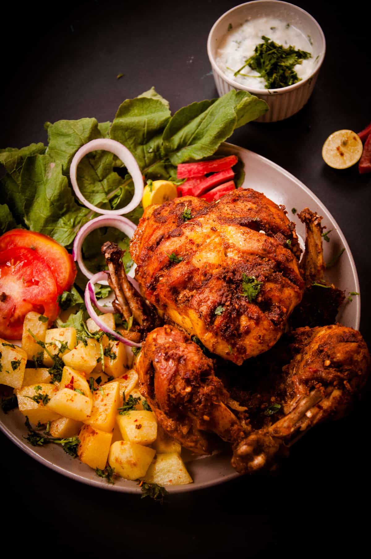 A orange roasted chicken on a silver plate.