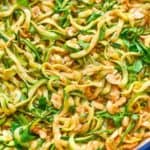 A close-up of a pan full of zucchini noodles and cashews