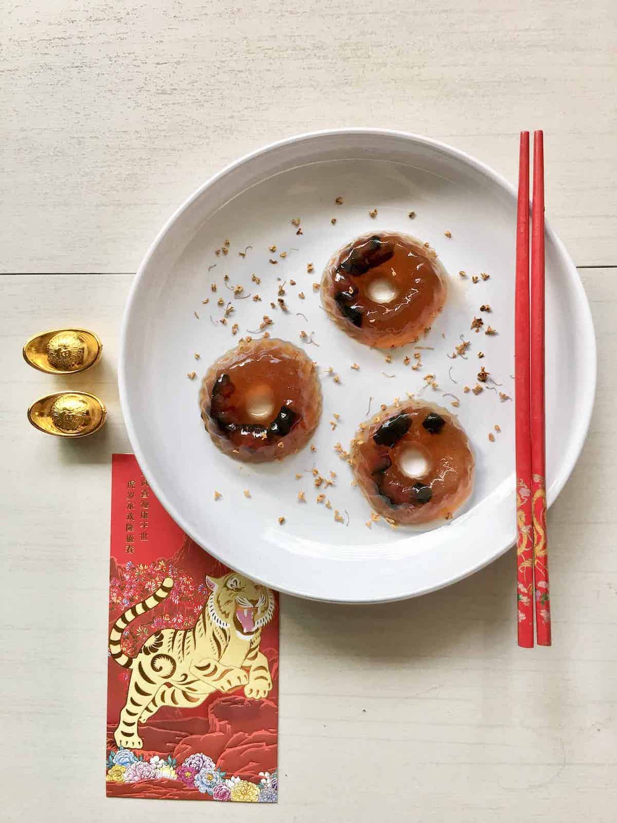 3 dried Chinese plum jellies with Chinese New Year decorations around them