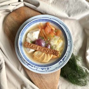 A close-up of coconut chicken soup with ginger and lots of ingredients