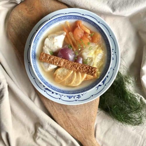 A close-up of coconut chicken soup with ginger and lots of ingredients