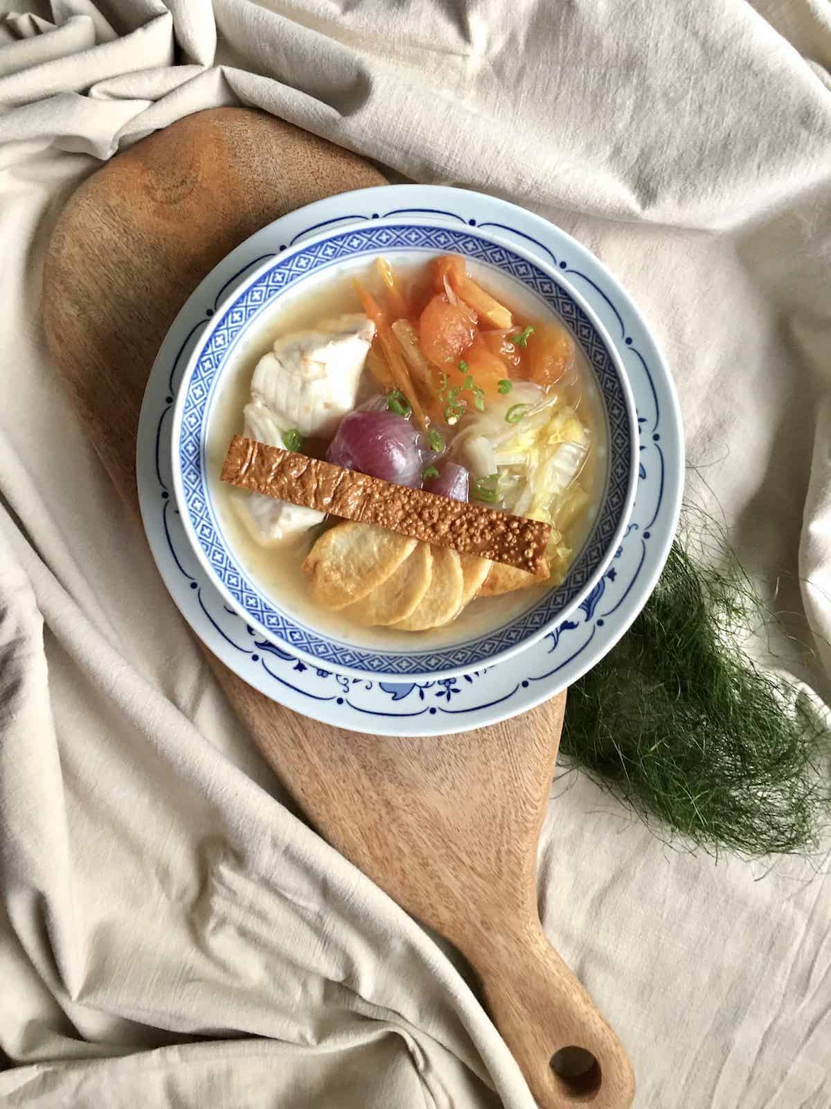 A close-up of coconut chicken soup with ginger and lots of ingredients