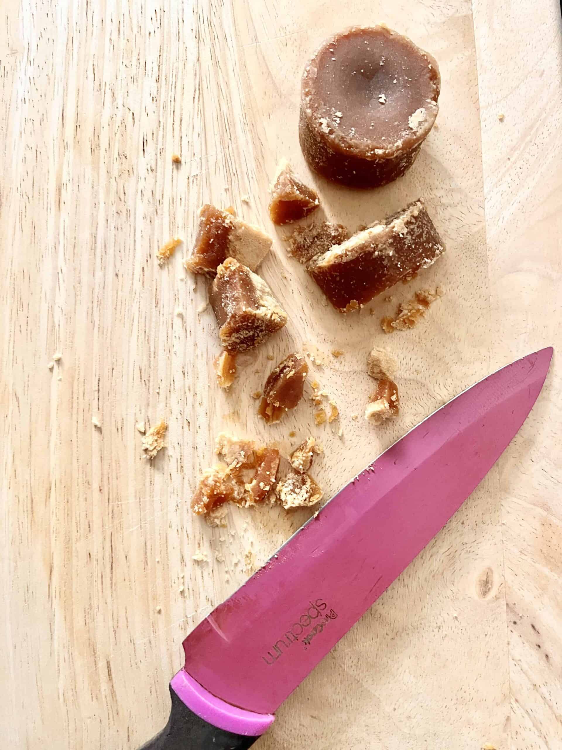 Cutting a cylindrical block of coconut caramel into smaller pieces.