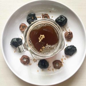 A glass of Chinese preserved plum tea with its ingredients