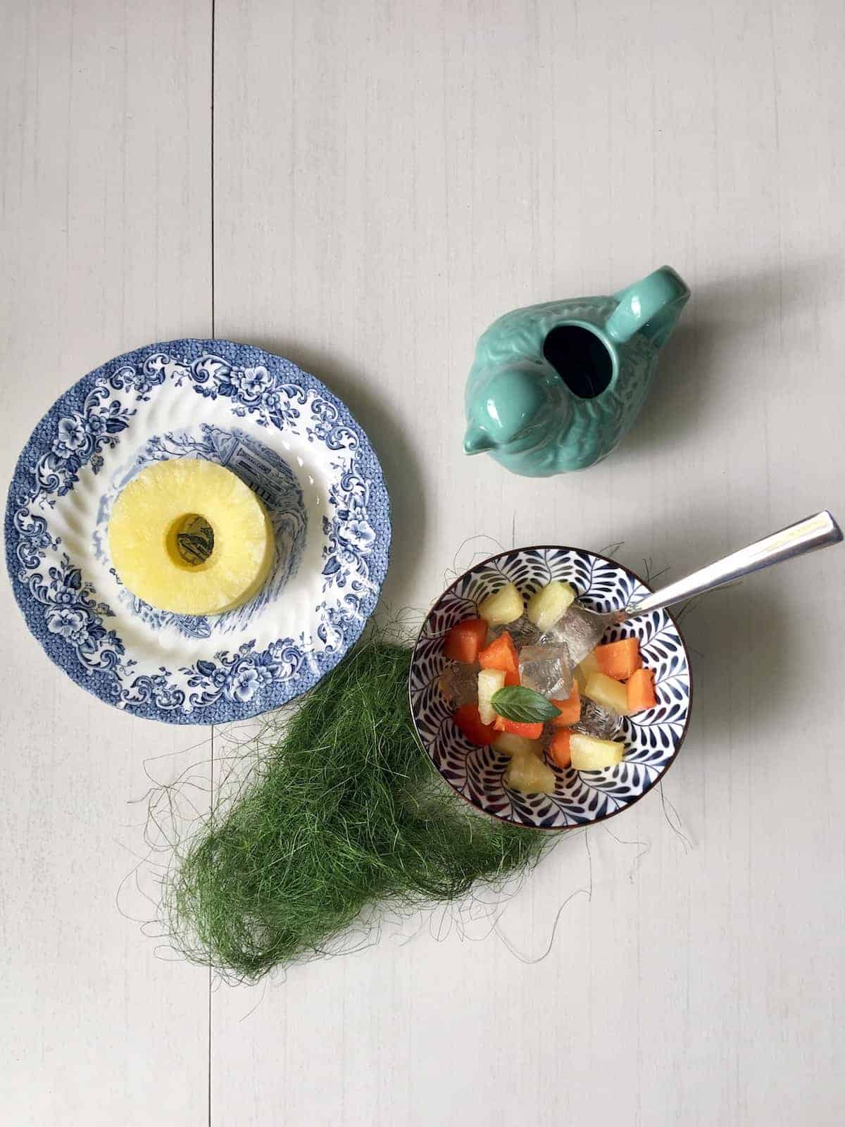 A bowl of fruit and jelly salad with pineapple on the side.