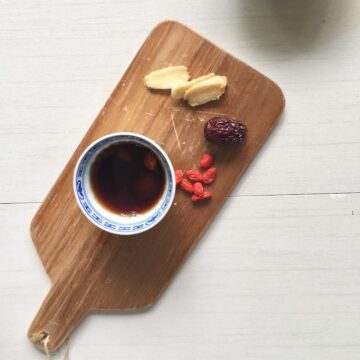 A cup of Chinese longan red date tea on wooden board.
