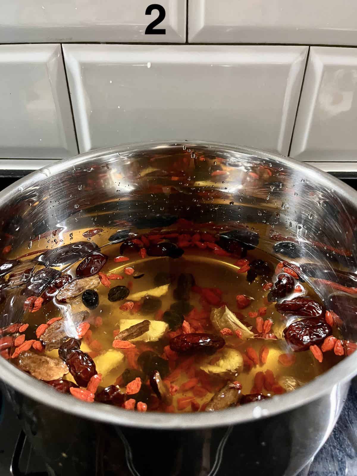 A pot of longans, red dates, ginger and goji berries steeping on the stove.