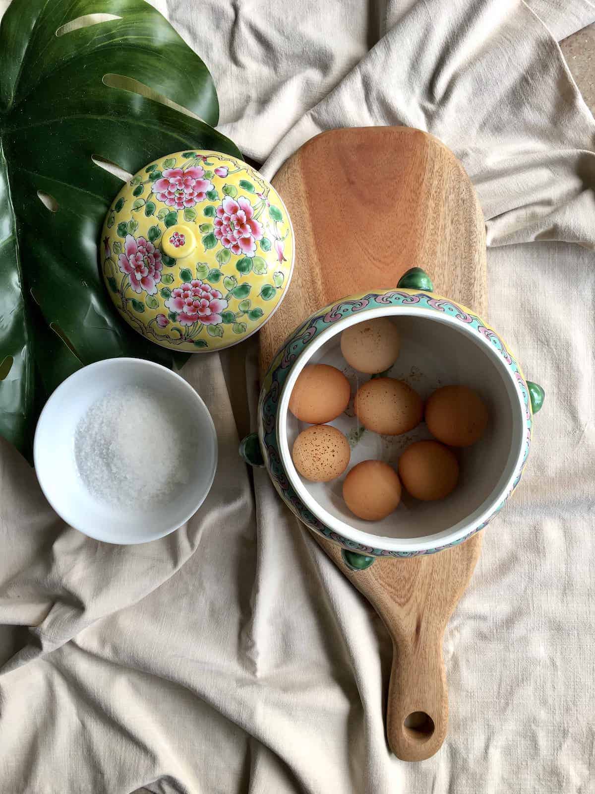 Eggs in salt brine in a yellow Peranakan kum cheng container.