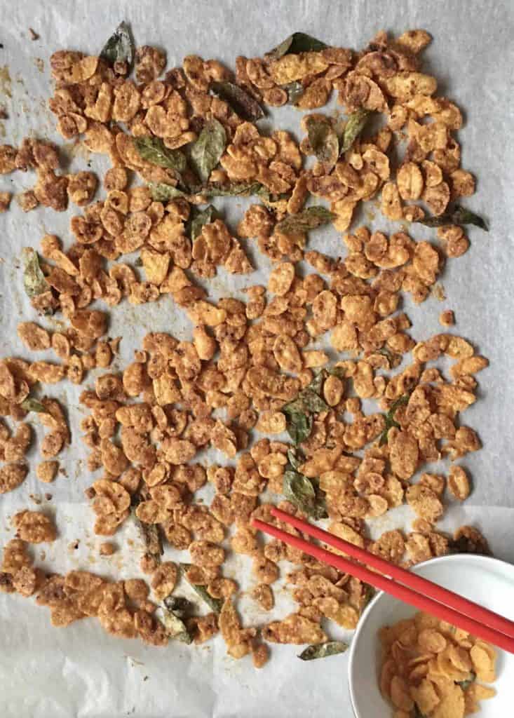 Crispy salted egg yolk cornflakes drying on parchment paper.