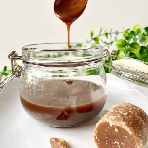 A wooden spoon scooping coconut caramel sauce out of a jar next to Gula Melaka Palm Sugar.