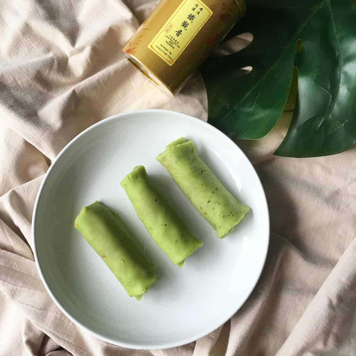 3 kueh dadar or pandan coconut rolls on a plate