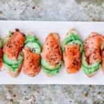 A row of salmon and avocado canapes that look like watermelon slices