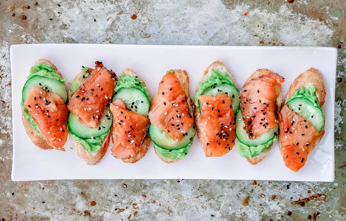 A row of salmon and avocado canapes that look like watermelon slices