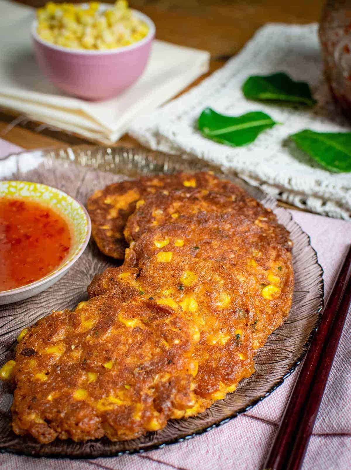Several brown Thai corn fritters on a fully laid out table