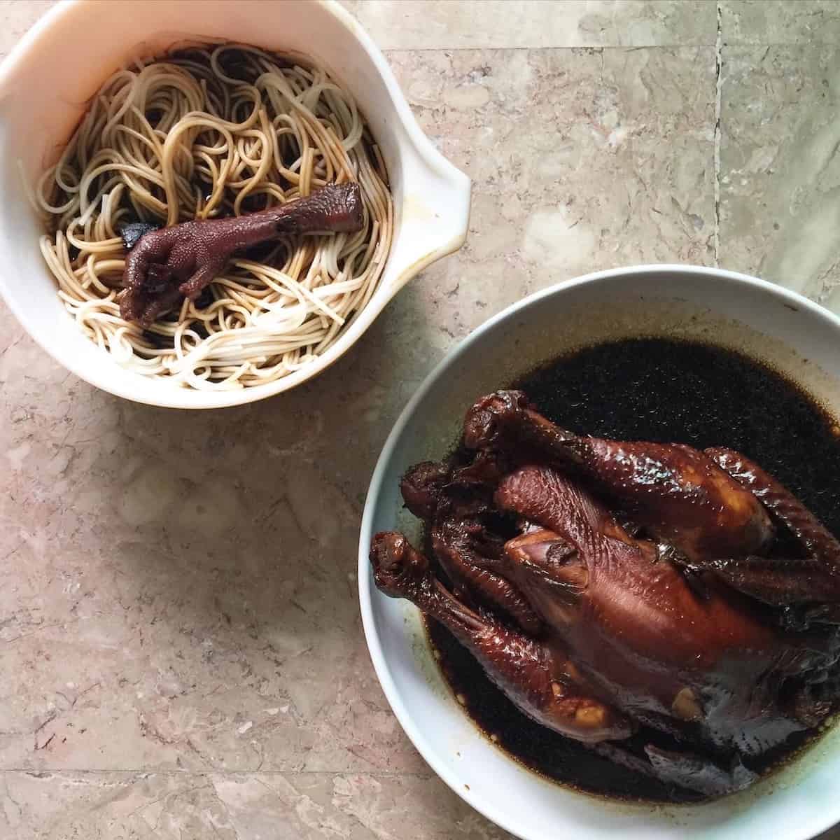 A whole soy sauce chicken next to noodles.