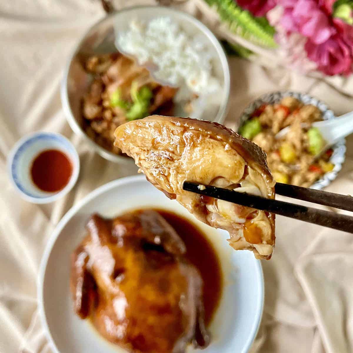 Using chopsticks to pick up a piece of Chinese soy sauce poached chicken.