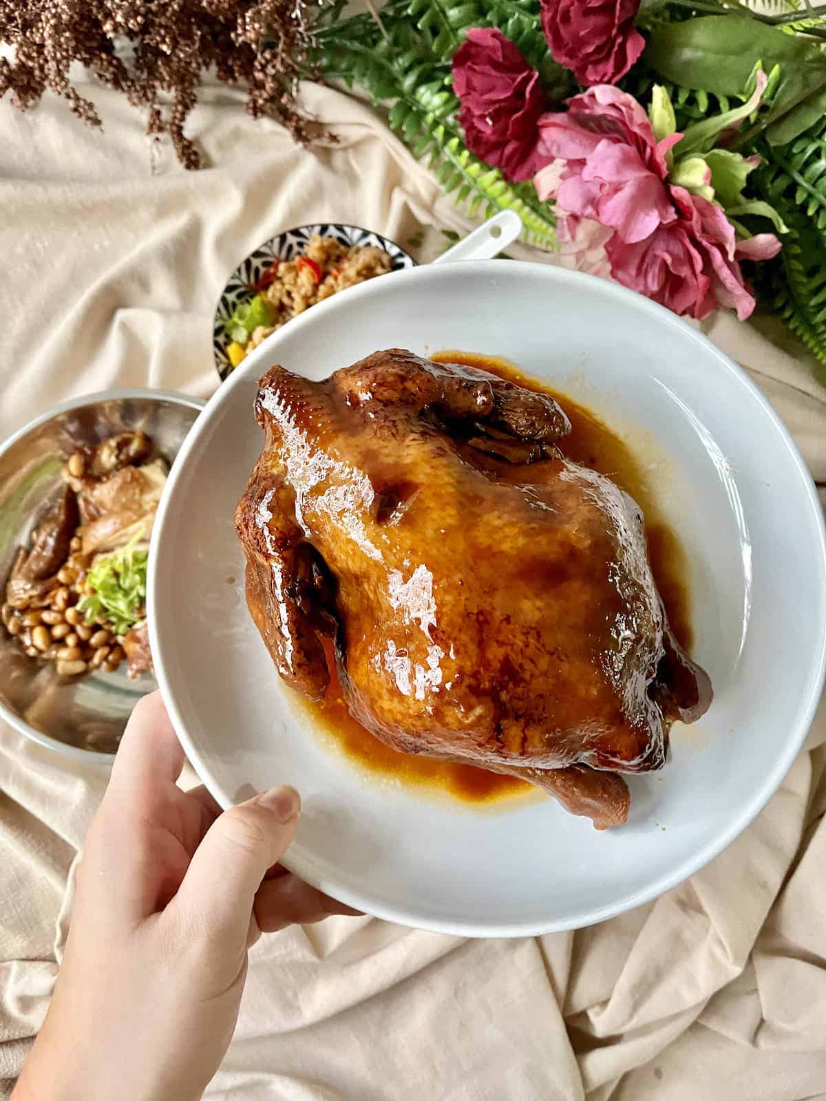 Close-up of a soy sauce whole chicken on a white plate.