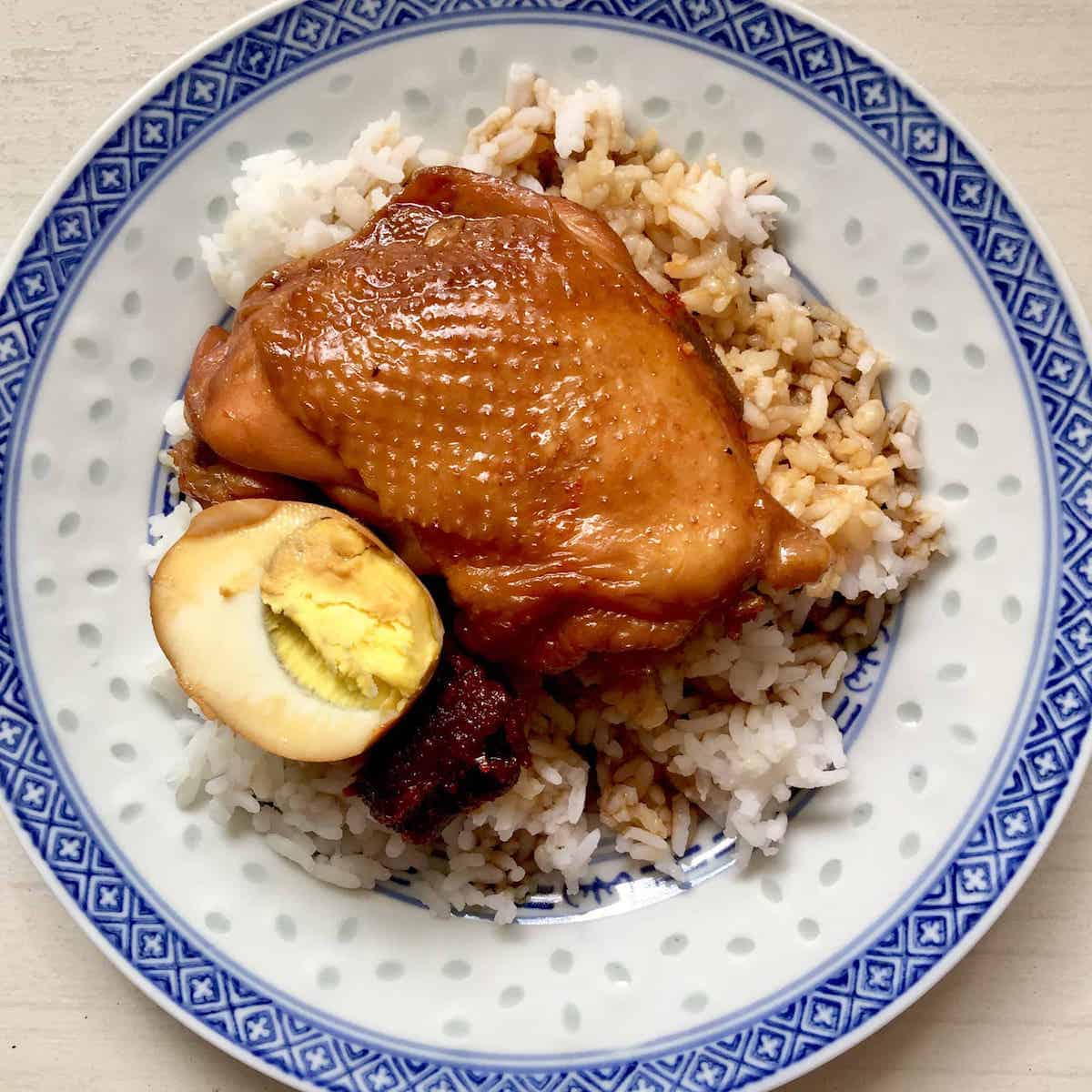 A plate of soy sauce chicken with hard boiled egg and spicy sambal