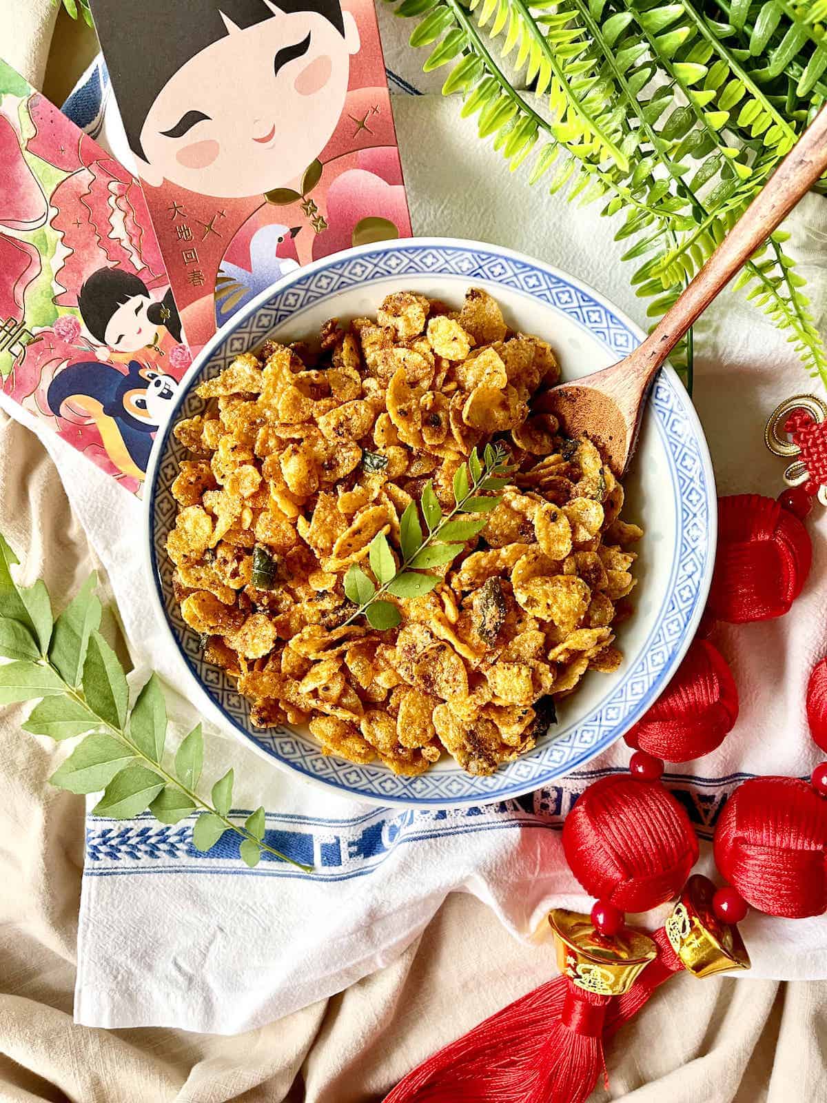 A big bowl full of salted egg cornflakes amongst Lunar New Year decorations.