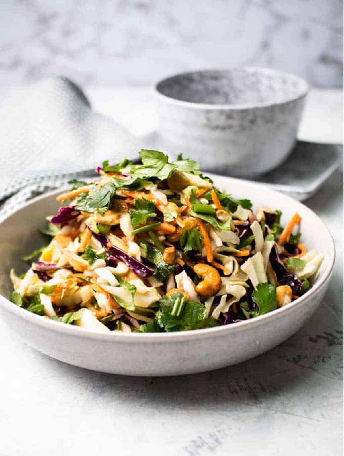 A plate filled with slaw and cashews in an Asian-inspired sauce