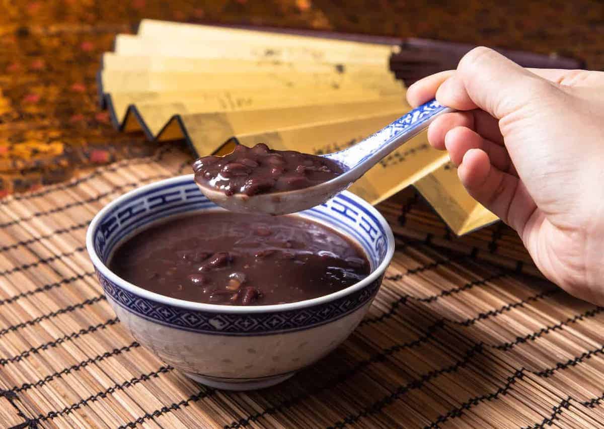Close-up of someone scooping red bean soup out of a bowl