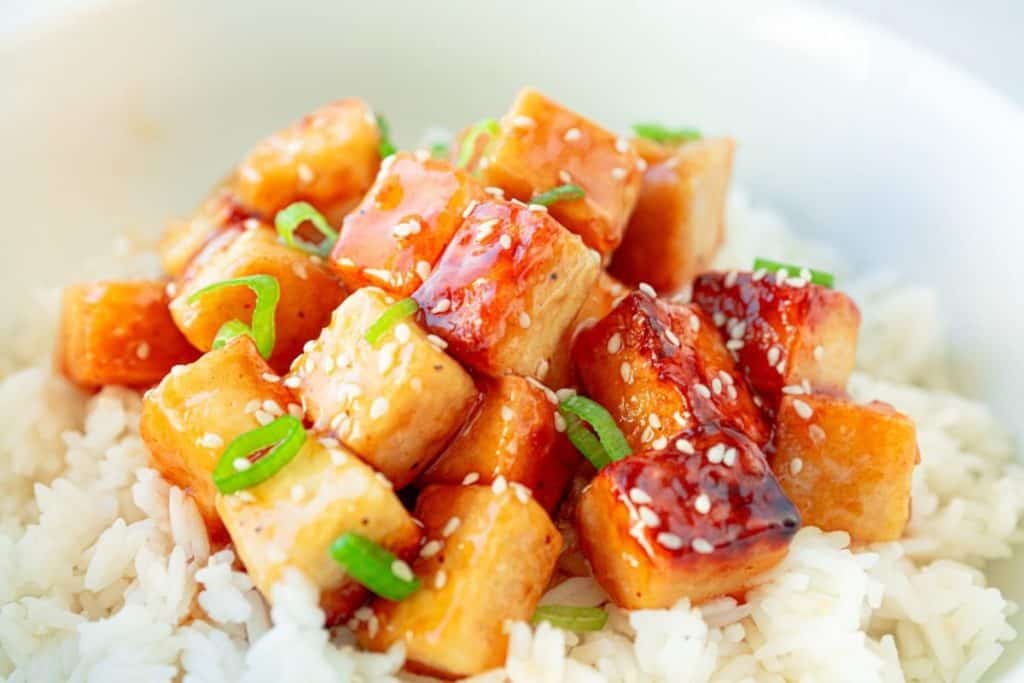 Close-up of tofu in a vegan orange sauce on rice