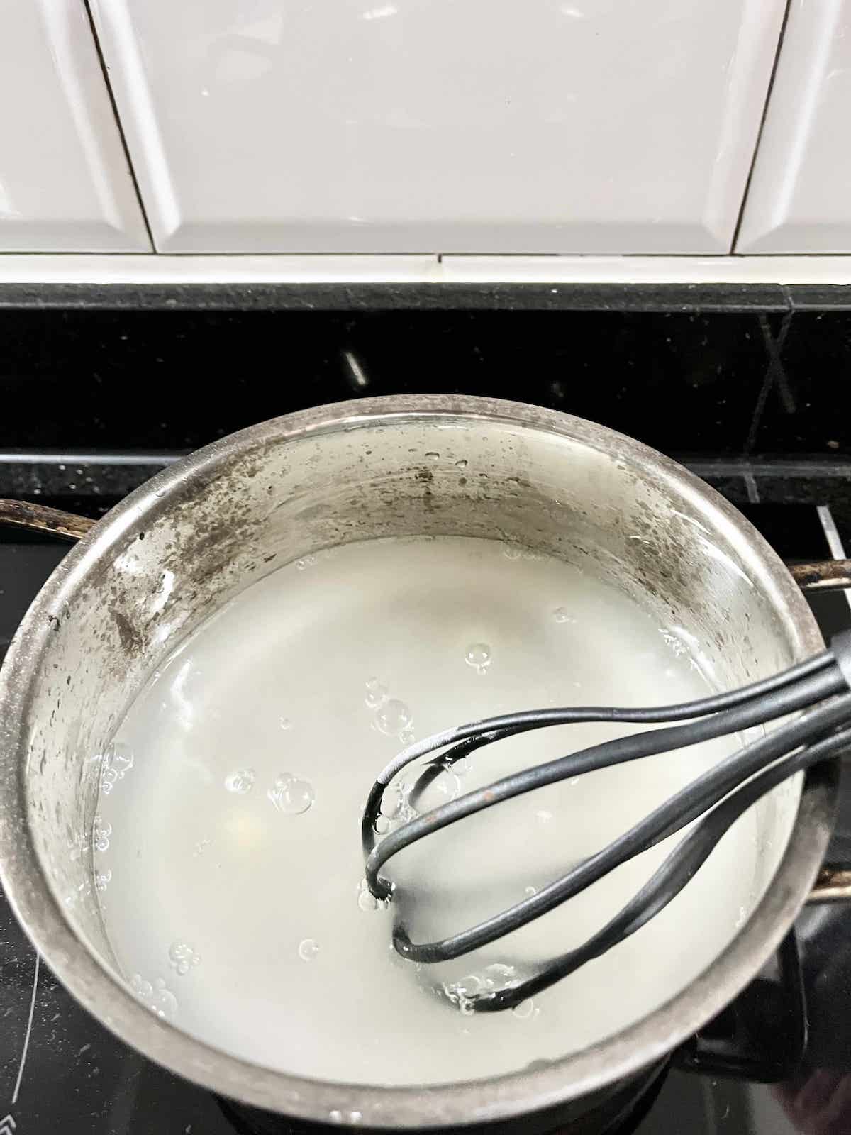 Whisking agar agar powder into a pot of cold water.