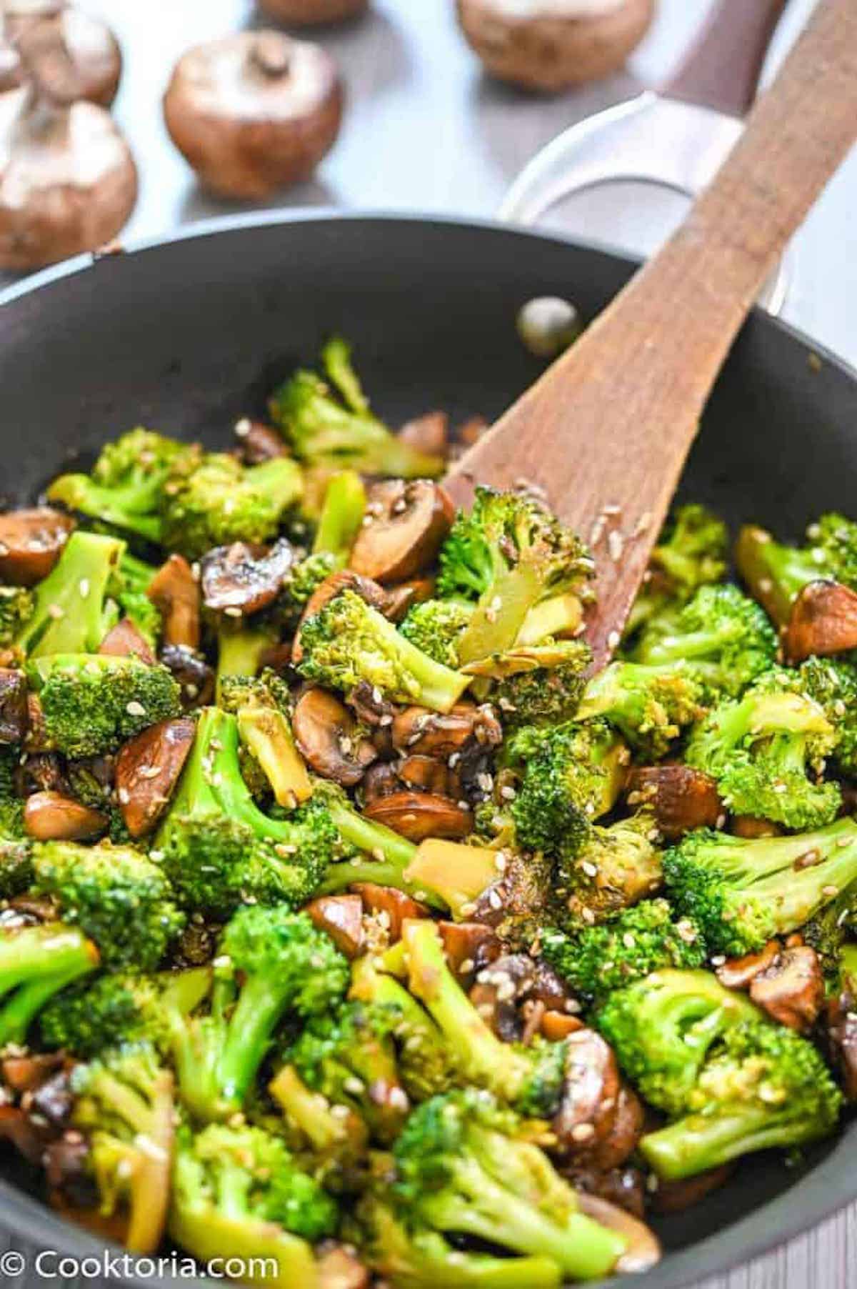 Close-up of broccoli and mushrooms in a skillet.