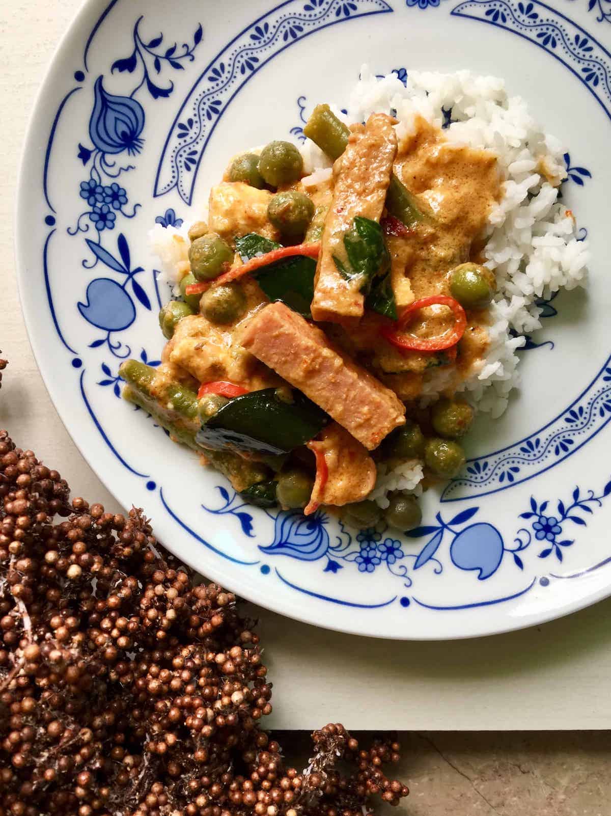 Thai-inspired curry with pea eggplants and pork, scooped over rice.