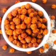 A bowl of orange chickpeas coated with ranch mix in a white bowl.