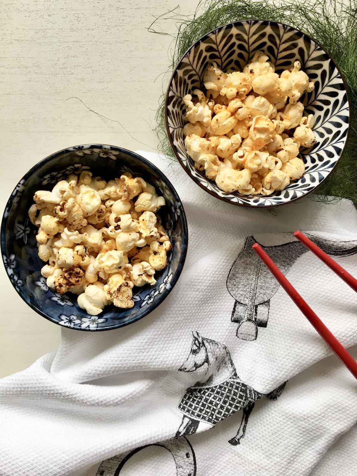 2 bowls of spicy popcorn, 1 with sugar and chilli crisp added to make sweet and spicy popcorn