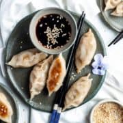 5 vegan gyoza with dipping sauce on a plate.