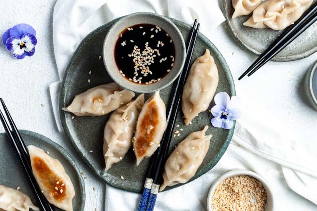 5 vegan gyoza with dipping sauce on a plate.