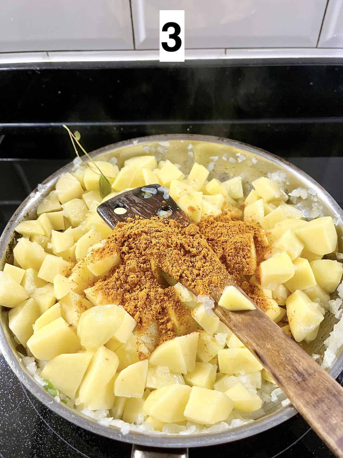 Stir frying potatoes in curry powder.