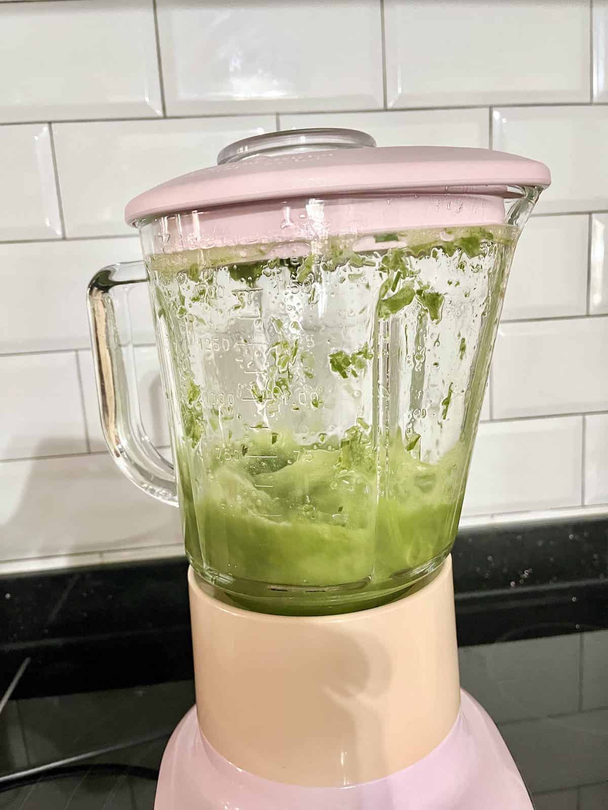 Pandan leaves and water being blitzed in a blender.