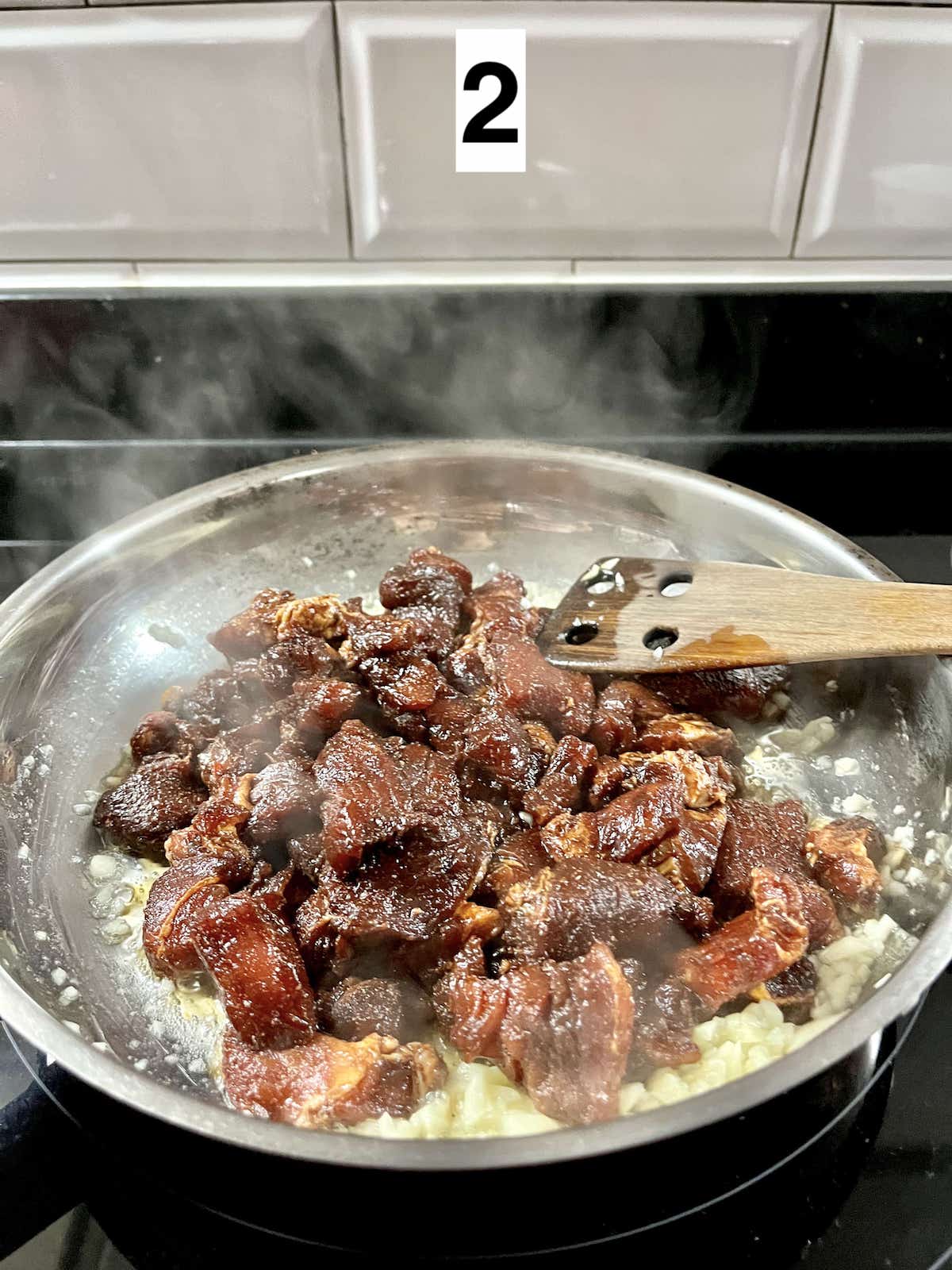 Lightly browning pork cubes in a pan.