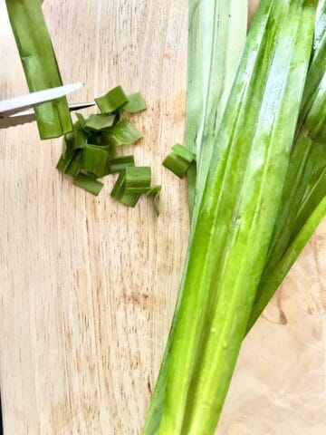 A bunch of fresh pandan leaves next to cut up leaves.