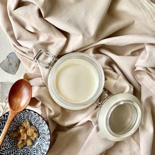 A jar of pure white lard on a tablecloth next to a bowl of lardons.