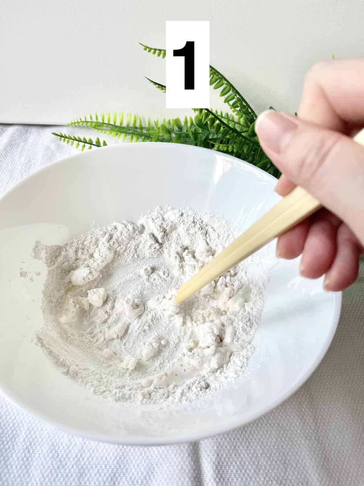 Stirring glutinous rice flour, water, sugar, salt and sesame oil with chopsticks.