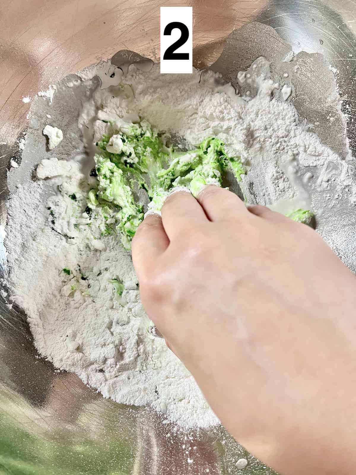 A hand mixing glutinous rice flour, pandan flavouring and water.