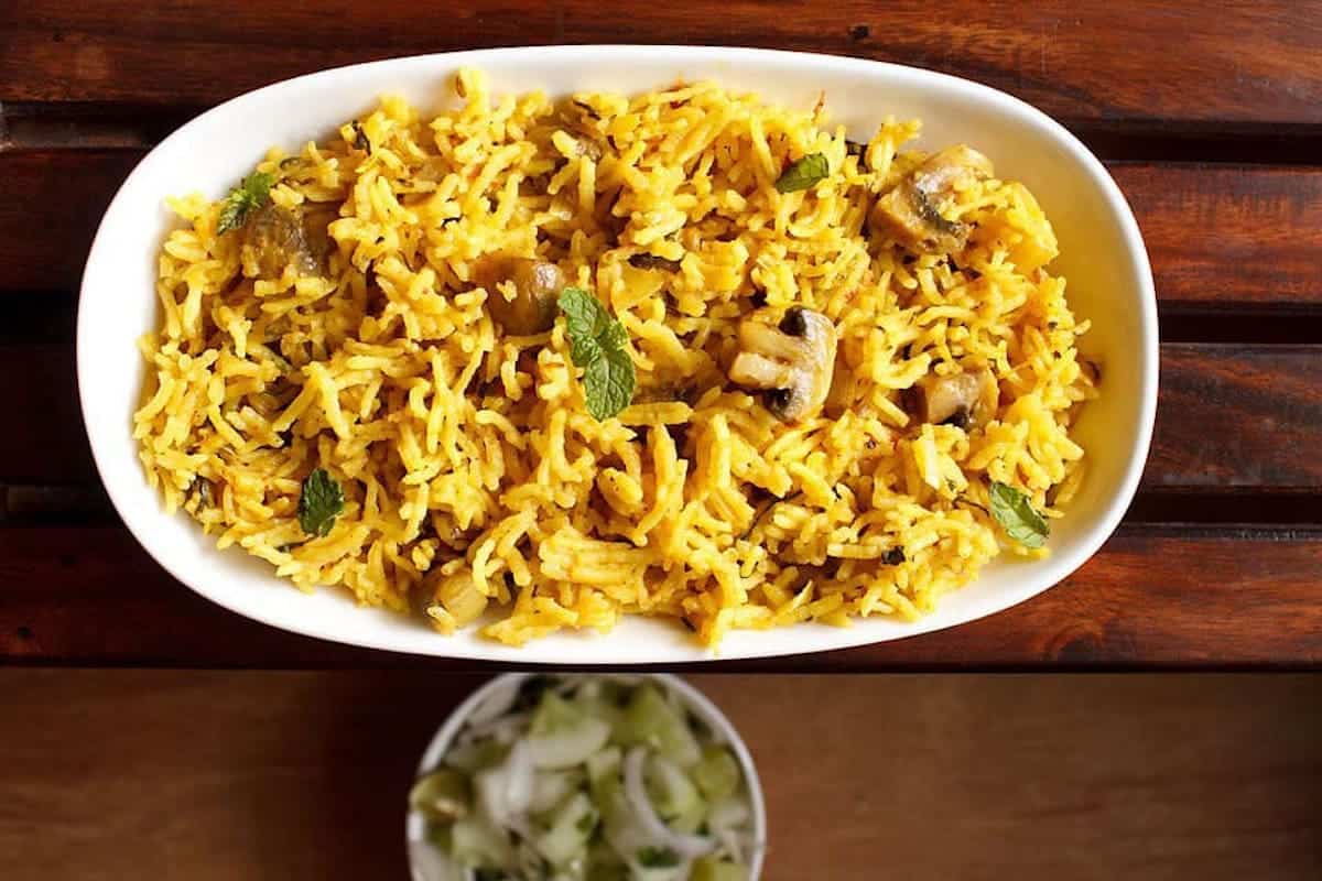 Yellow mushroom rice on a white platter.