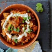 A bowl of red mushroom masala in an orange bowl.