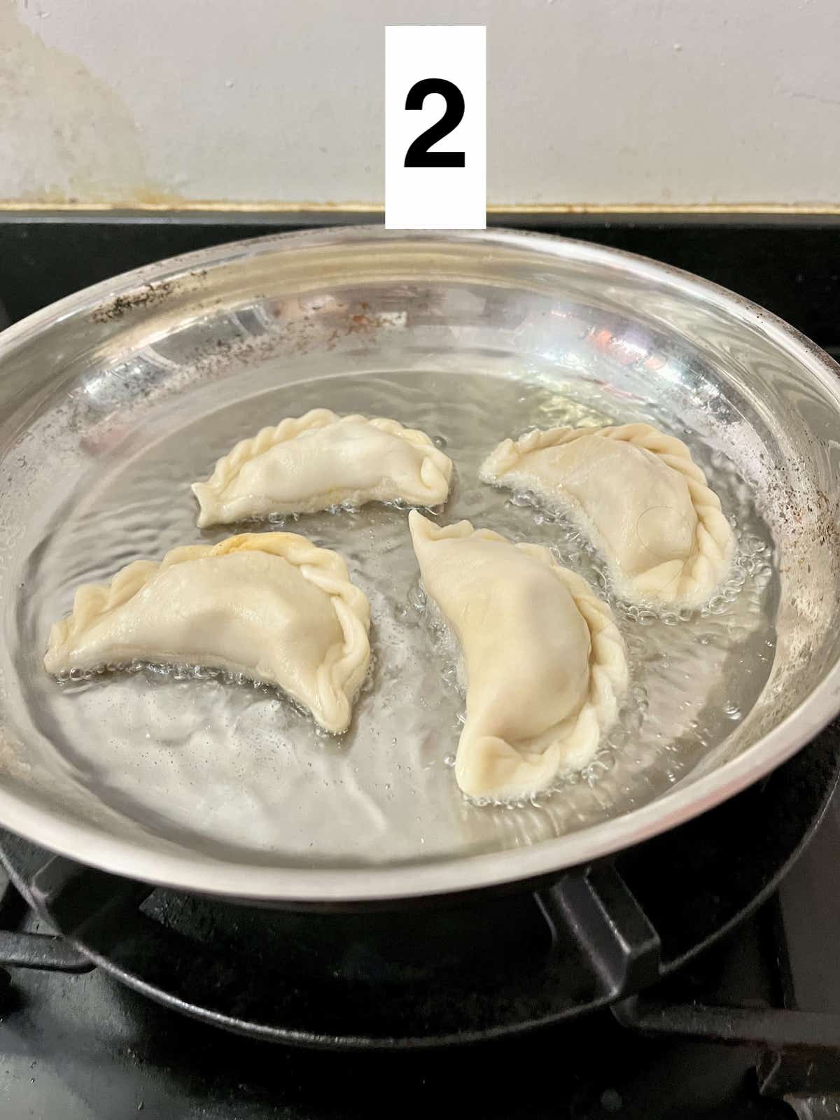 4 curry puffs in a pan of hot oil.