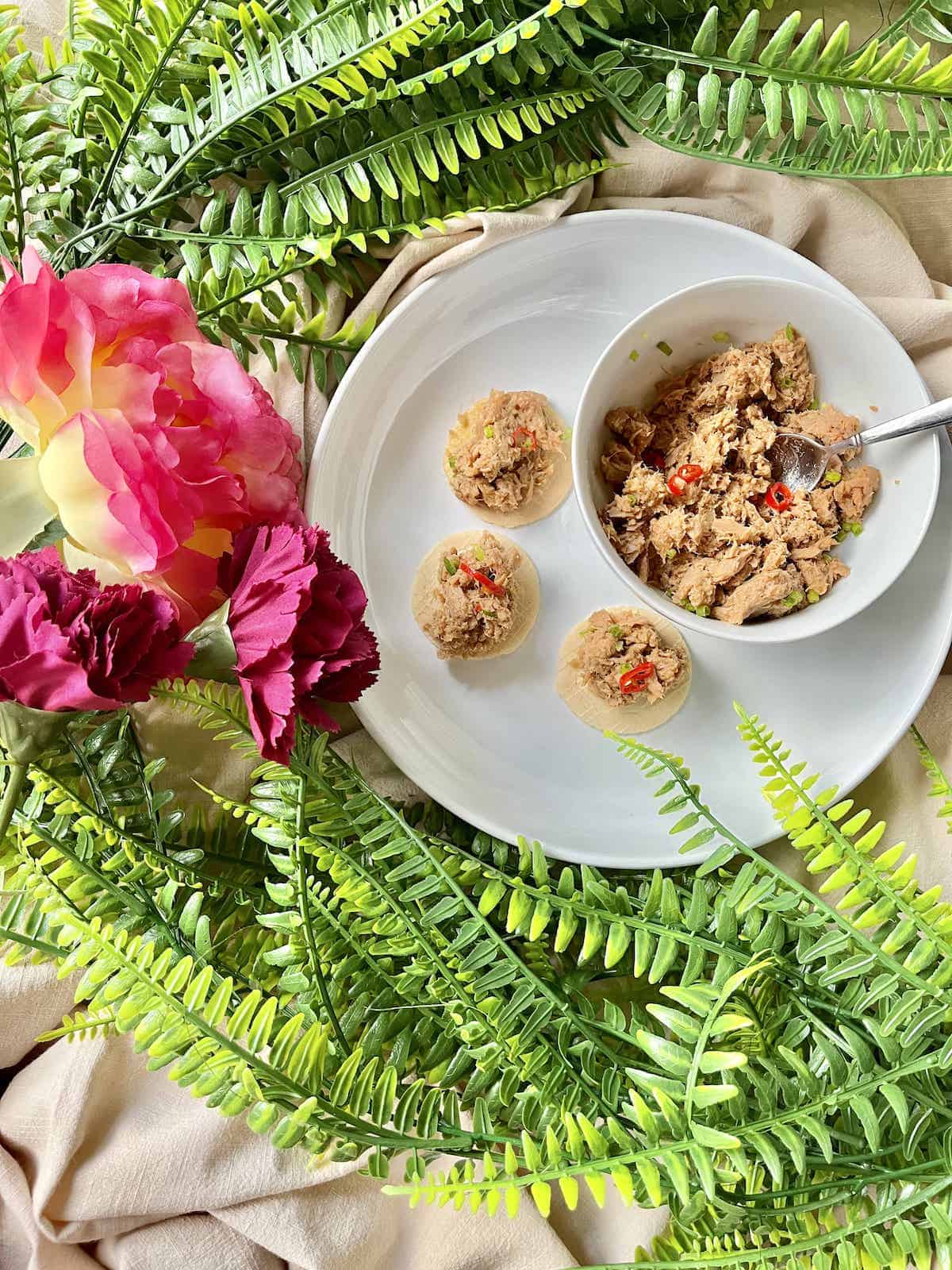 A bowl of spicy canned tuna dip next to 3 crackers.