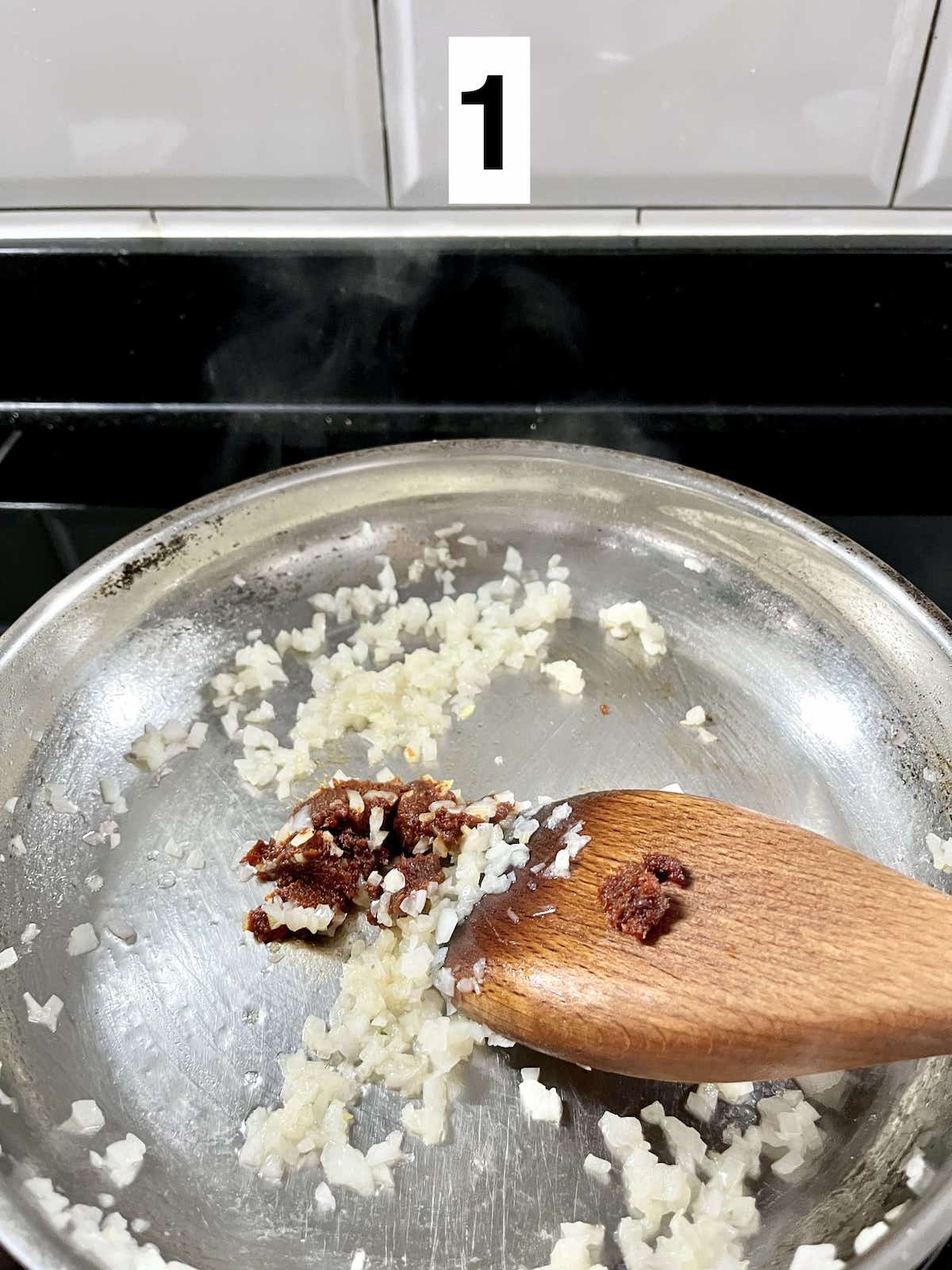 Sautéing minced onions and sambal in a pan.