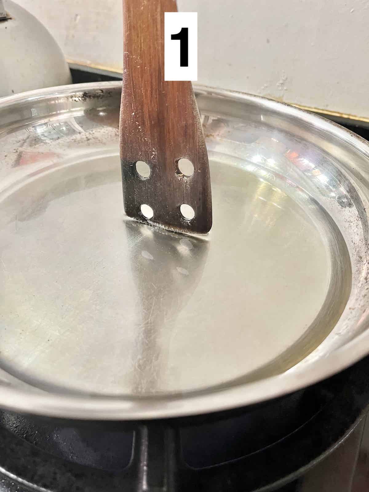 Inserting a wooden spatula into a pan of hot oil.