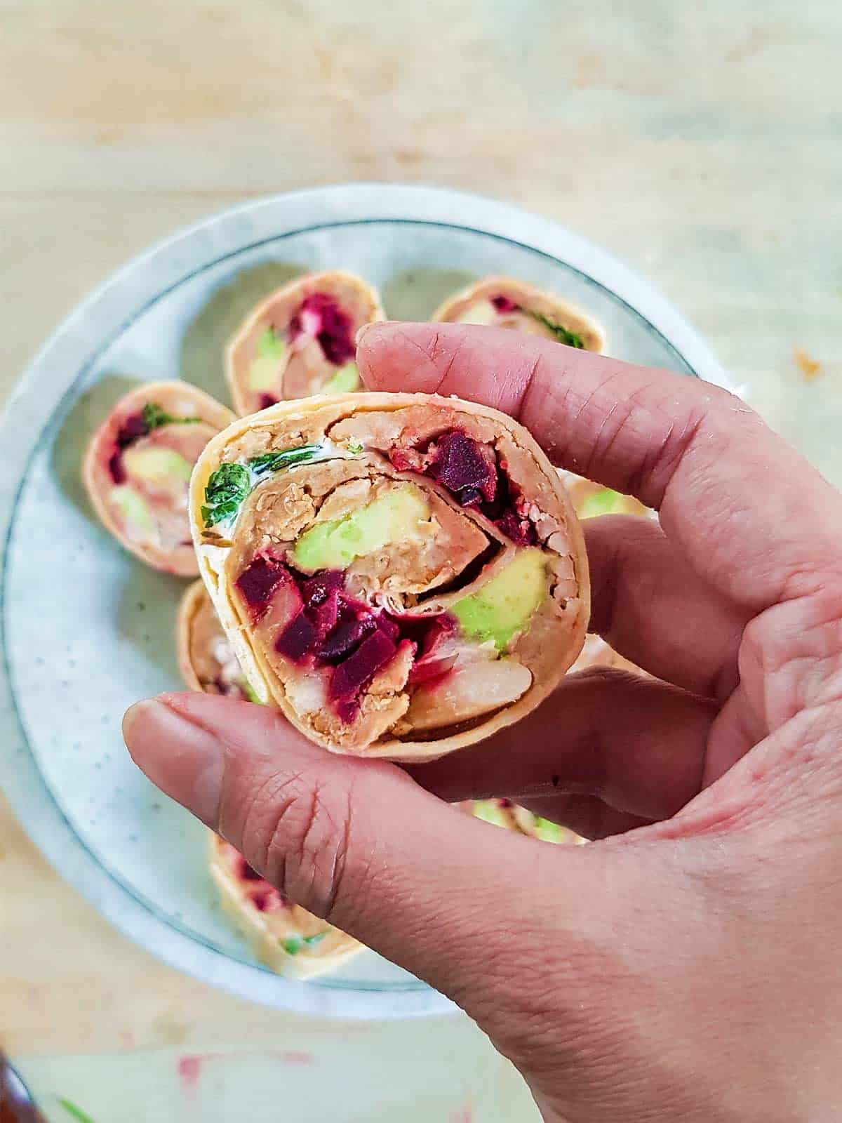 A hand holding a vegan pinwheel appetiser