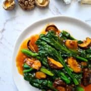 Chinese broccoli & mushrooms on a white plate.