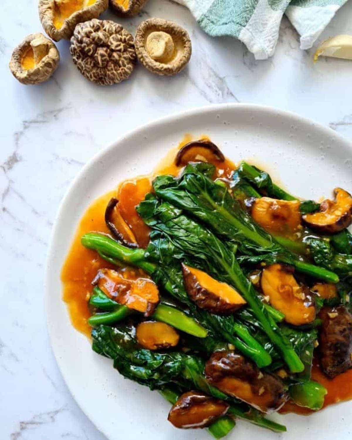 Chinese broccoli & mushrooms on a white plate.