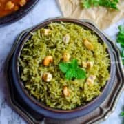 A plate of green pudina rice with toasted nuts on top.